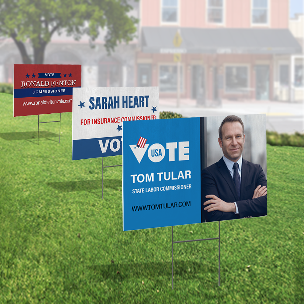 Multiple political campaign yard signs displayed on lawn with metal stakes