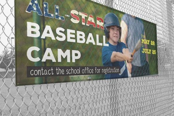 Mesh banner for a baseball camp on a chain link fence